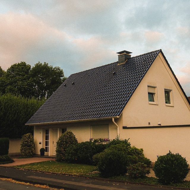 Et gult hus med et nyt sort tag og en skorsten